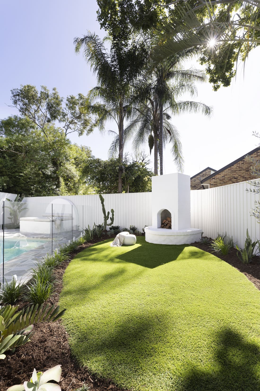 Custom built white firepit and faux grass backyard