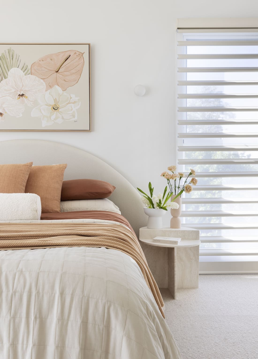 Curved bed with rust bedding and floral art