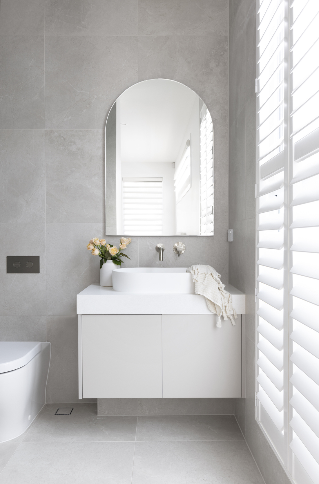 Ensuite bathroom with white vanity and arch mirror