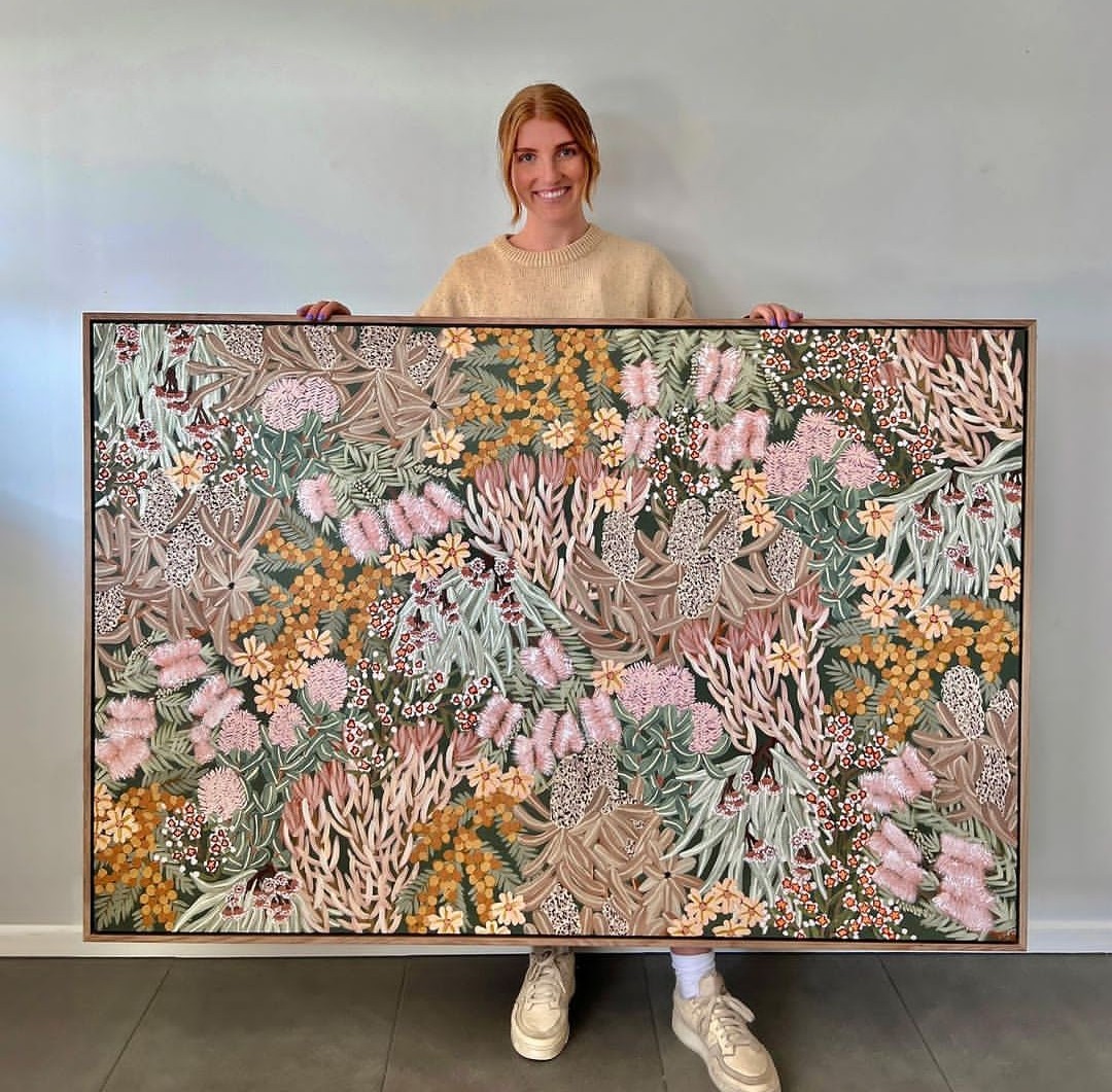 Amy Gibbs holding floral artwork in neutral tones