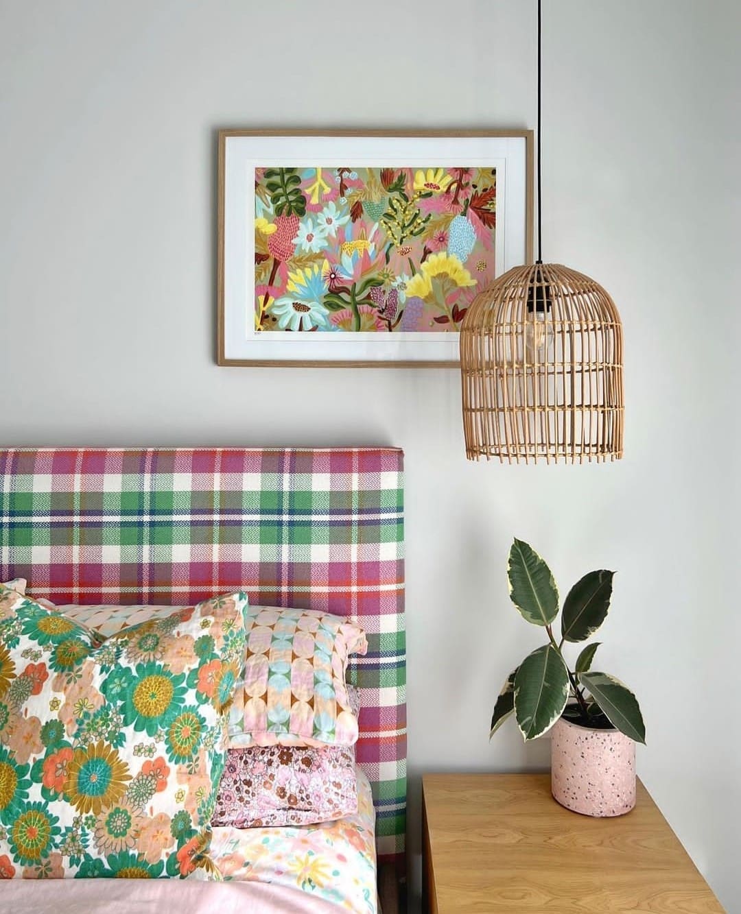 Checked bedhead and floral print on wall in bedroom