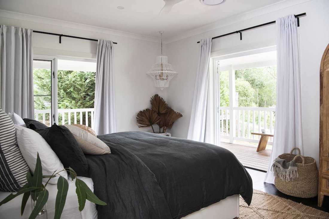 Grey bedding in bedroom with verandah view