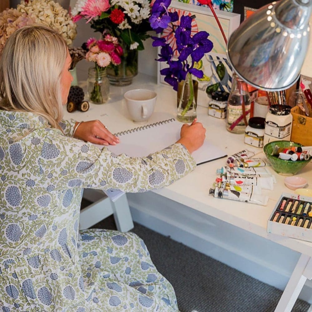 Alexandra Strong painting floral artwork at studio desk