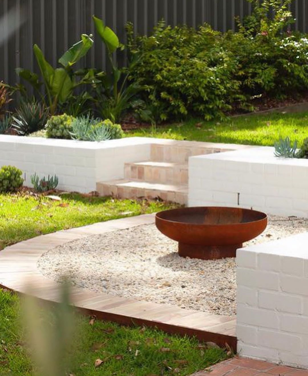 Rusty firepit with white painted brick wall