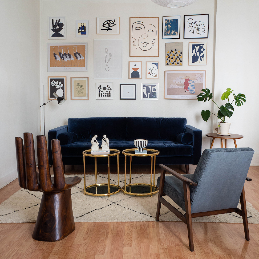 Graphic gallery wall with blue sofa and gold coffee table by Aplotica Studio