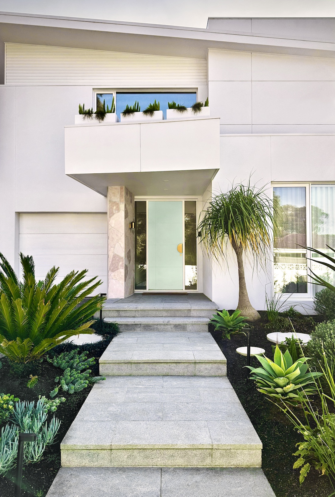 White exterior of home with landscaped gardens