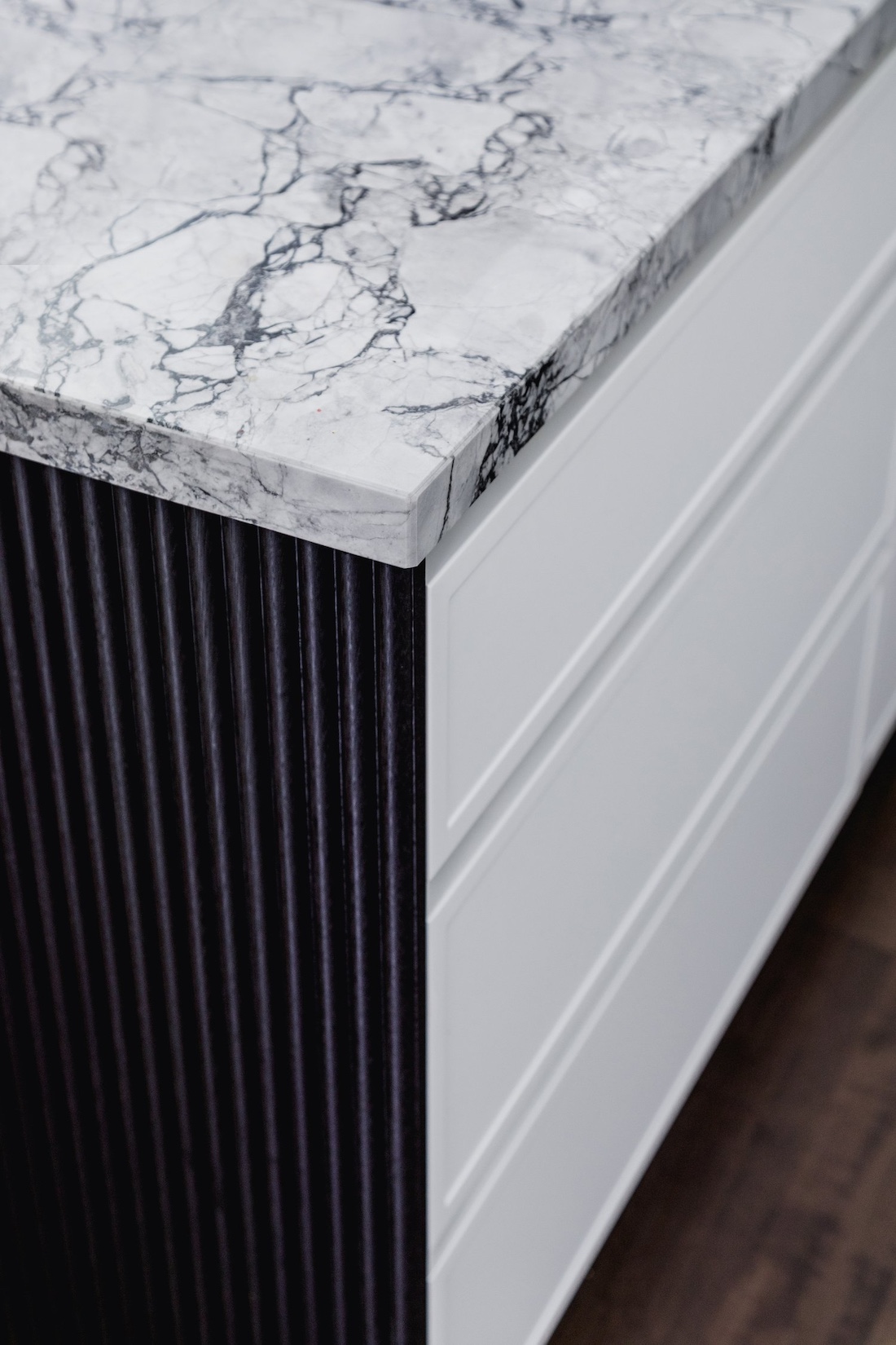 Marble benchtop, black batten side and white drawers in kitchen island of Wattle Valley Road by Picchio Interiors