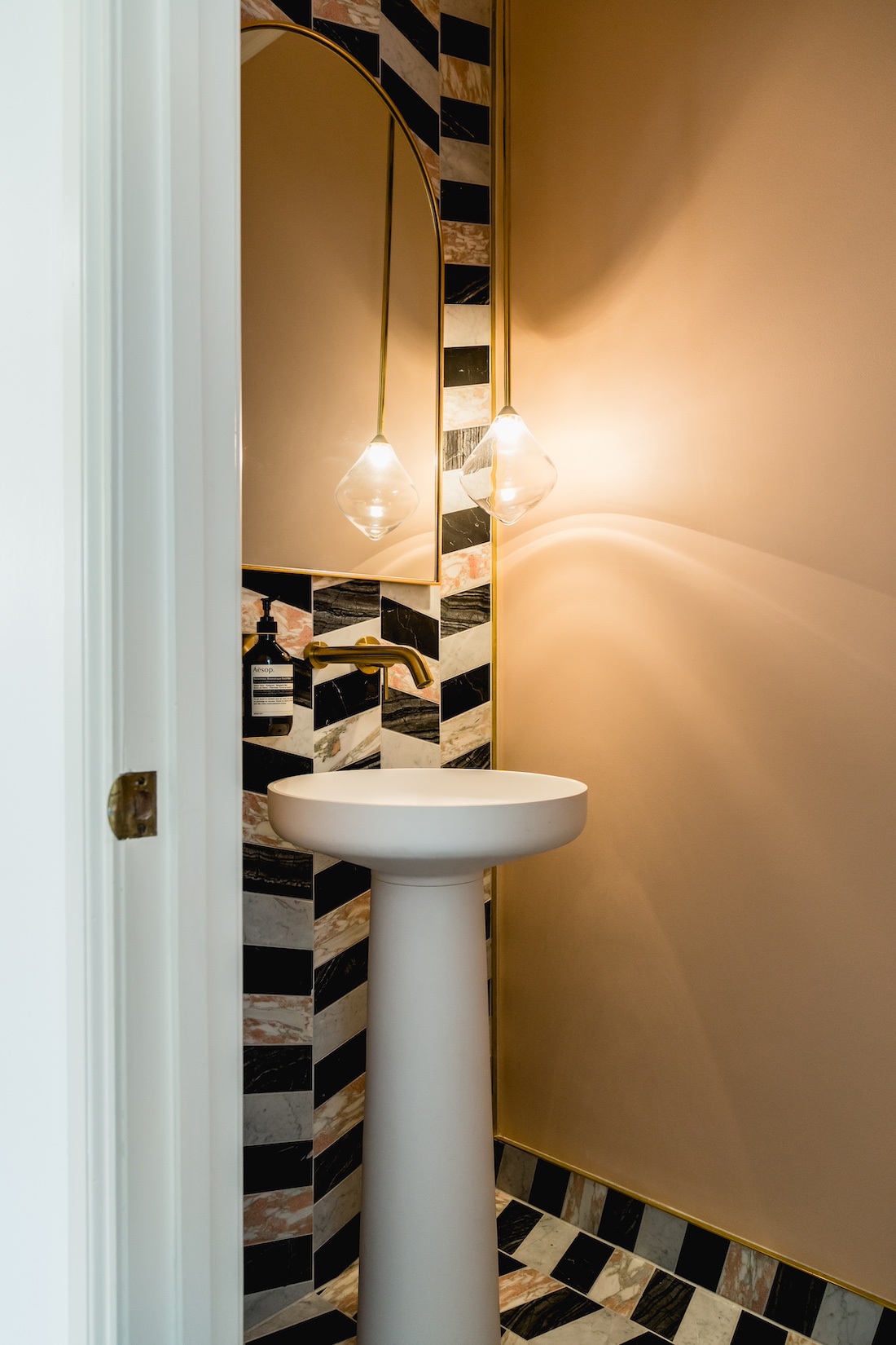 Carnegie Cottage black and white mosaic tiled wall with powder room pedestal bathroom