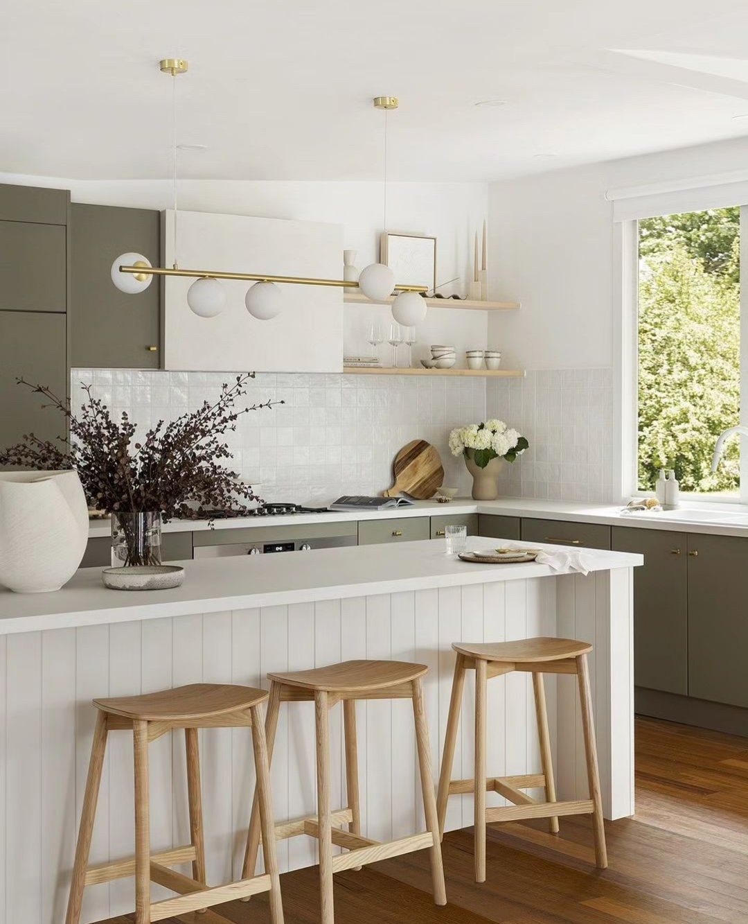 Green kitchen cabinetry with white island bench