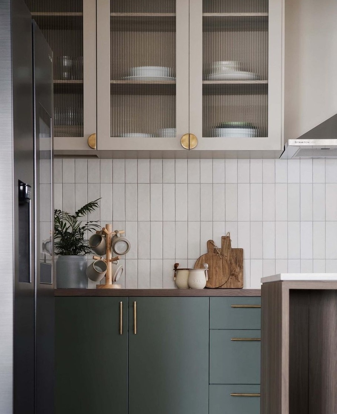 Dark green cabinetry with white long skinny tiles for back splash