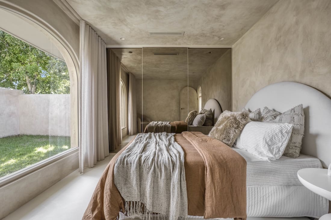 Bedroom with view through arched window to garden in Ruin X