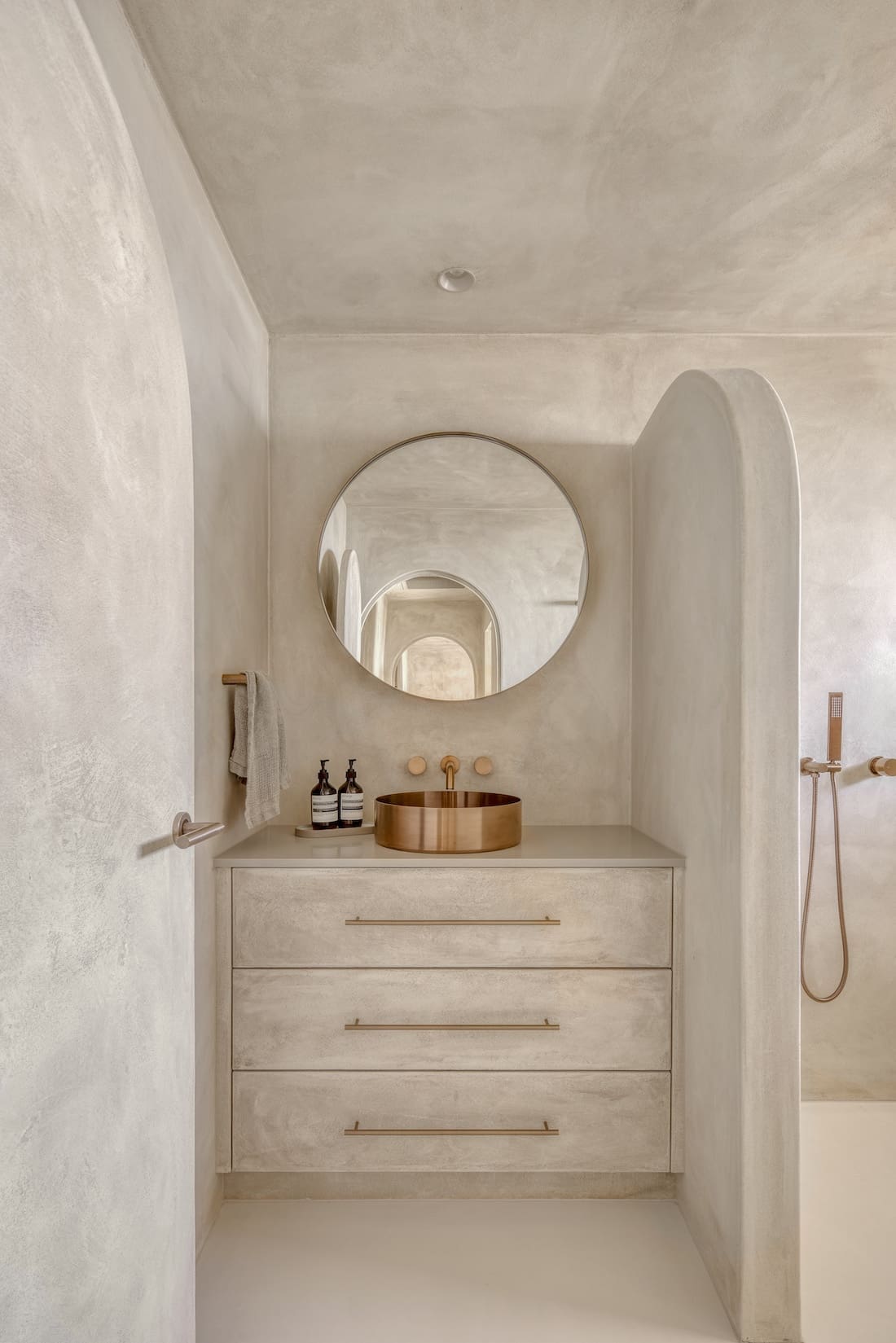 Round mirror and copper sink in Ruin X bathroom