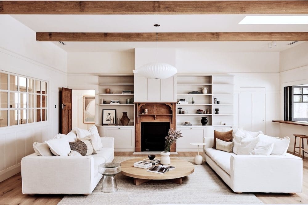 Living room with timber fireplace and overhead wooden beams in Rocklee House