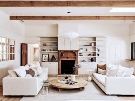 Living room with timber fireplace and overhead wooden beams in Rocklee House