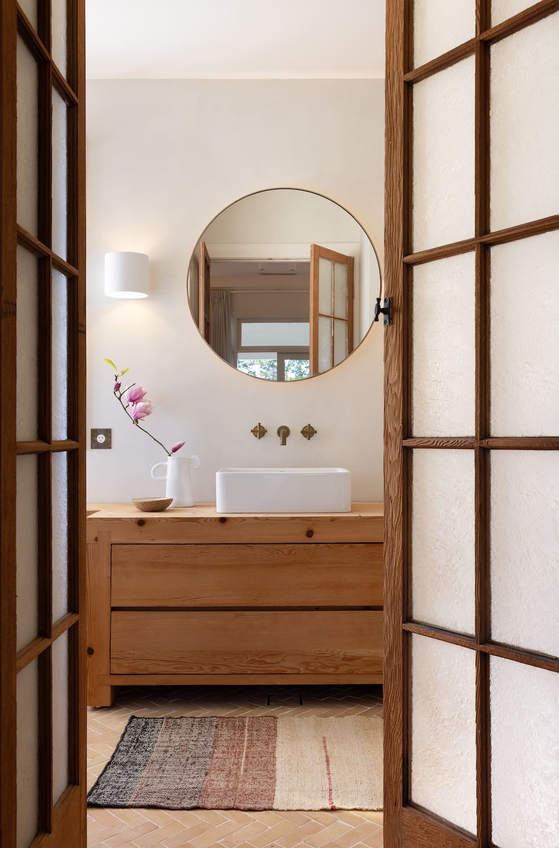 Round mirror in bathroom with timber and glass door at Rocklee House