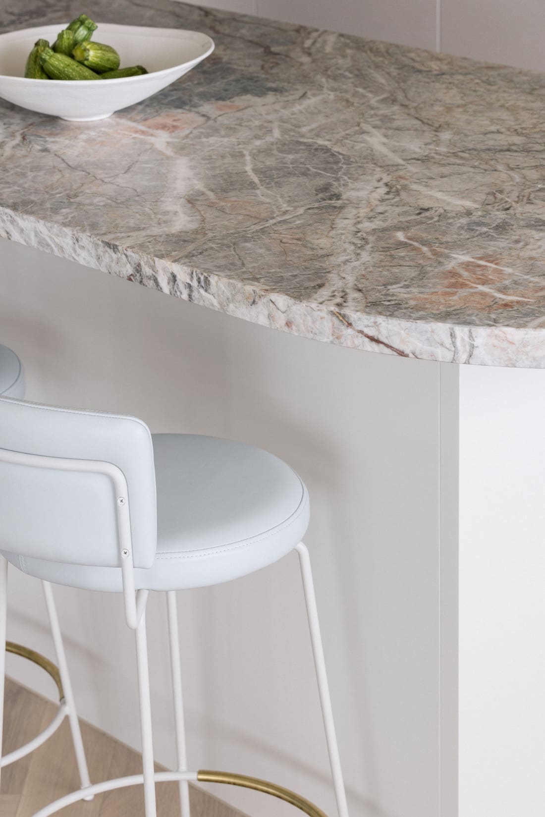 Curved island benchtop and white bar stools