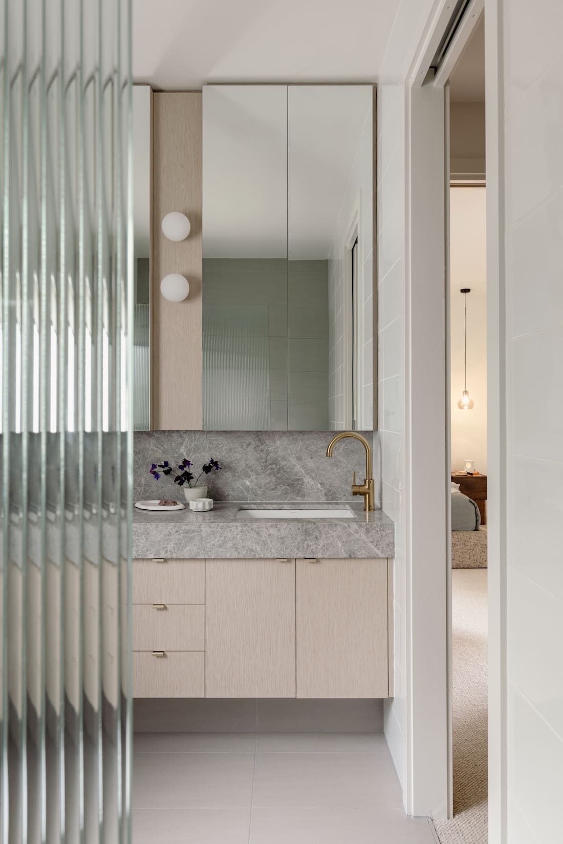 Bathroom with stone benchtops in bathroom makeover with reeded glass door
