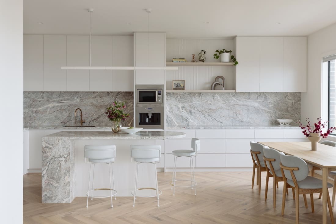 White and marble kitchen with curved island and herringbone flooring