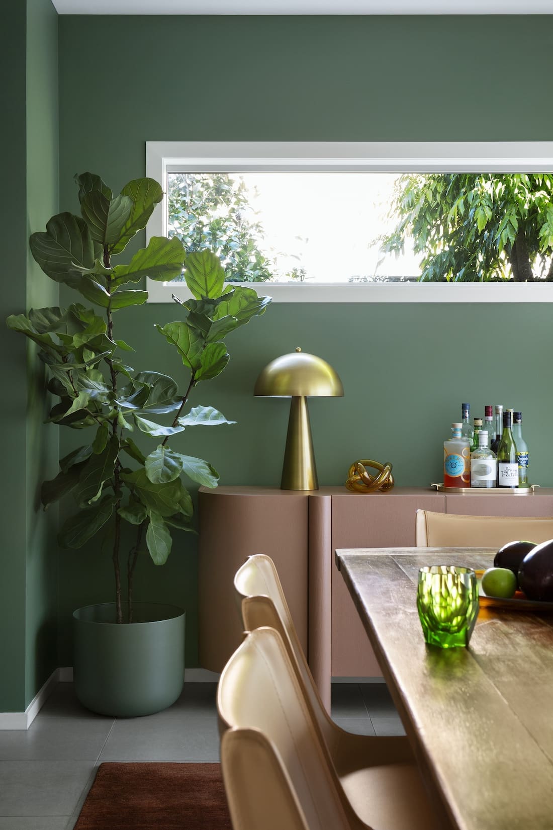 Dining room with green wall in Warm Embrace residence by The Stylesmiths