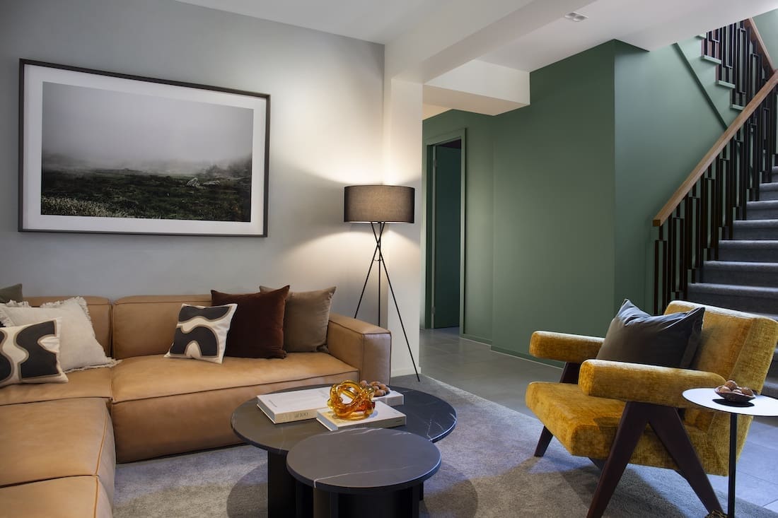 Living room with green walls in Warm Embrace residence by The Stylesmiths
