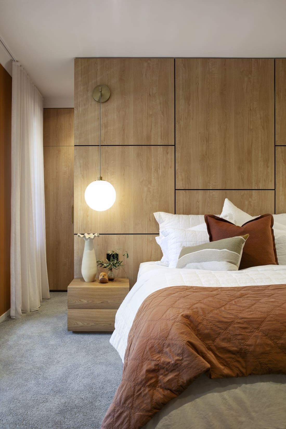 Timber feature wall behind bed in master bedroom of Warm Embrace residence by The Stylesmiths