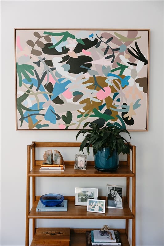 Colourful abstract art above small shelving unit in hallway