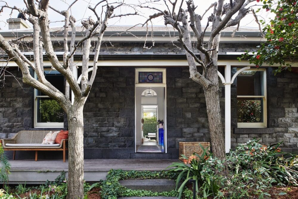 Front façade of Bluestone Sanctuary with original bluestone walls, heritage veranda and garden setting, redesigned by The Stylesmiths and YDM Studio.