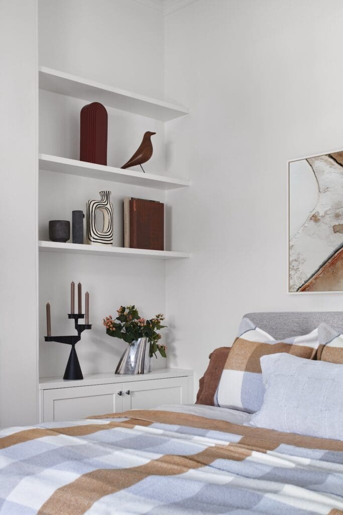Bedroom styling at Bluestone Sanctuary with built-in white shelving, curated decor and neutral bedding, designed by The Stylesmiths with architecture by YDM Studio.