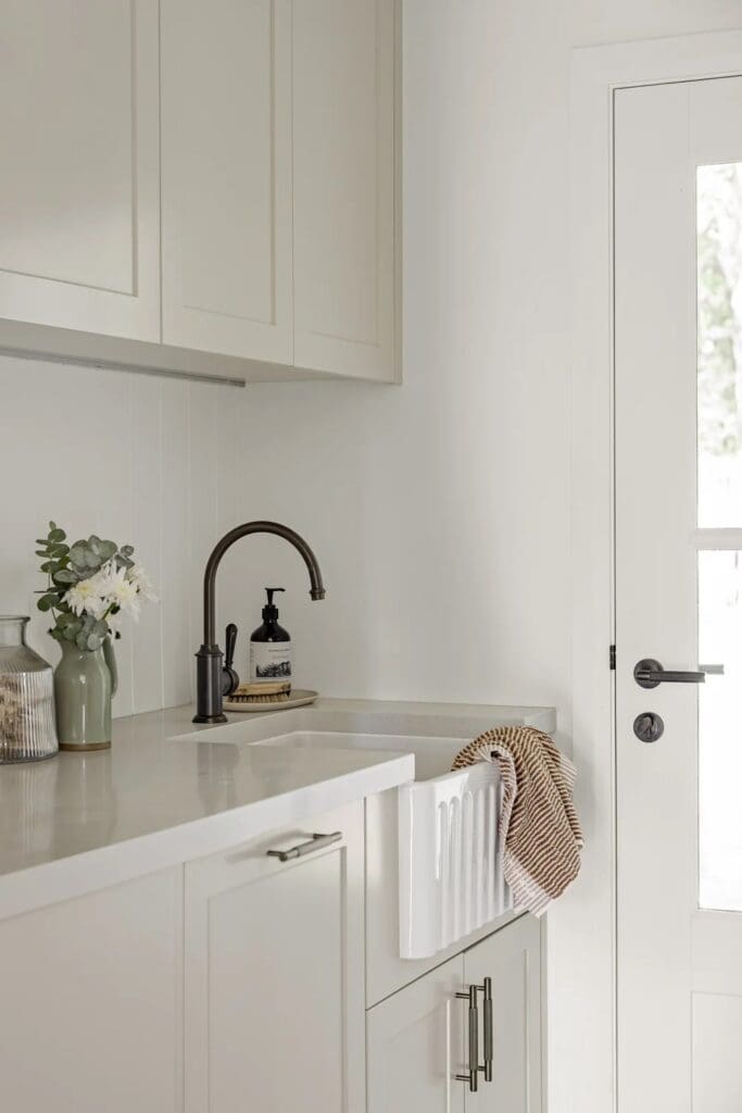 White laundry with farmhouse sink in Ewingsdale home