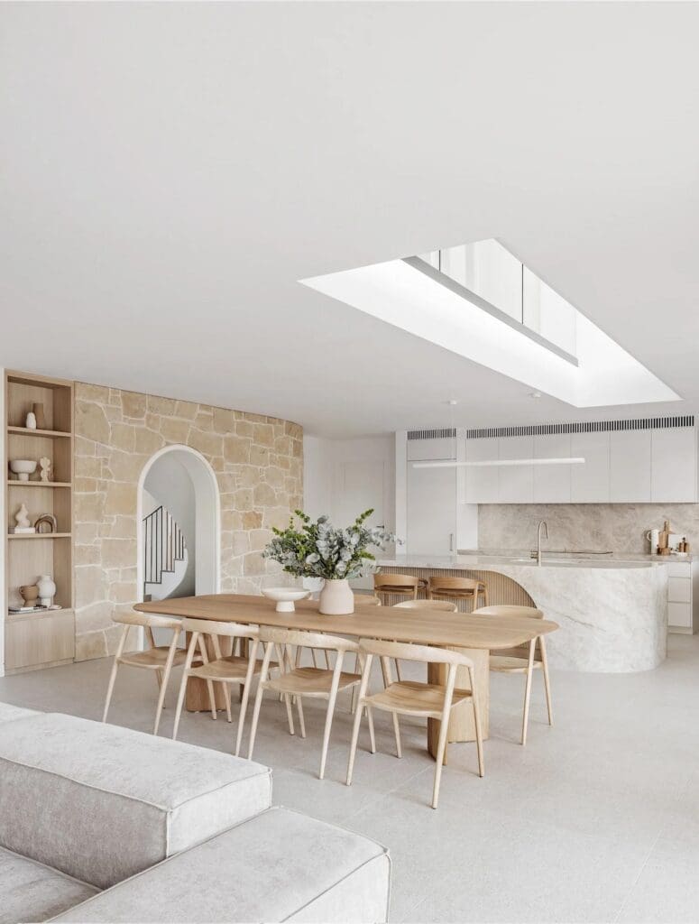 Dining room with large skylight and natural stone wall at The Stables Burraneer House