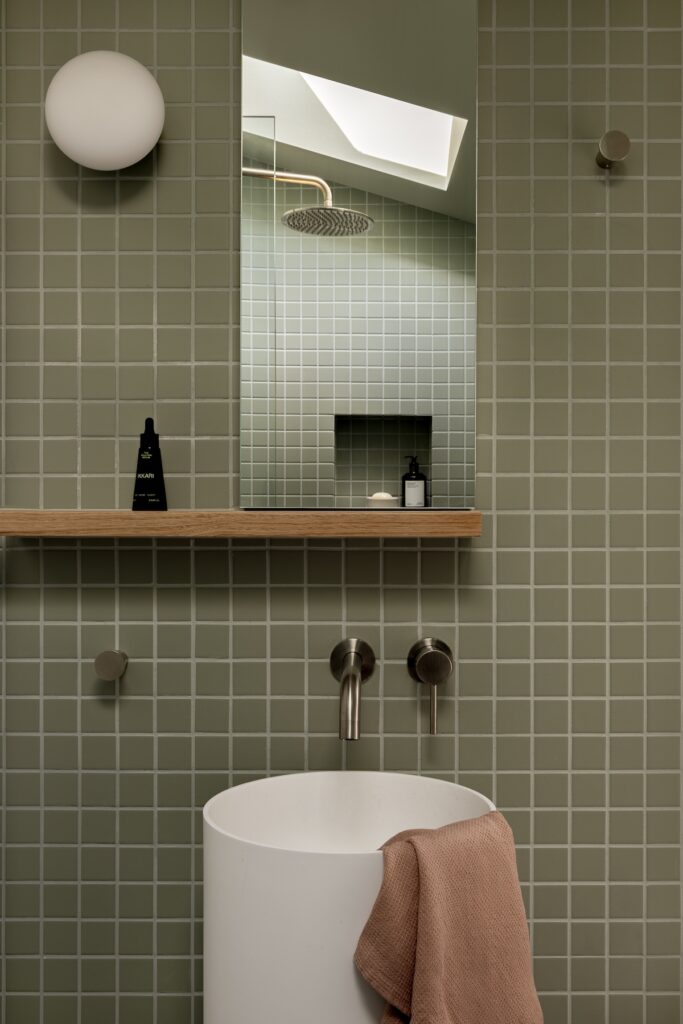 White pedestal basin in green grid tile bathroom