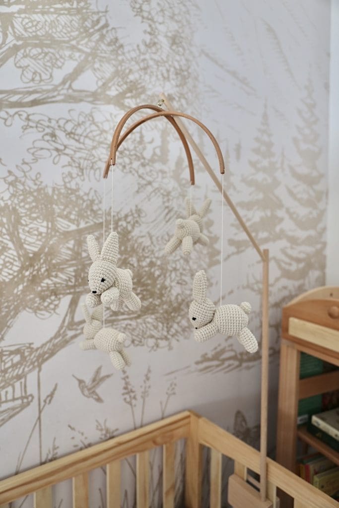 Bunny mobile over cot with woodland wallpaper in nursery