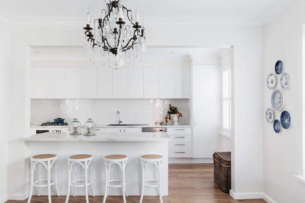 White kitchen with ornate chandelier in Patterned Sanctuary by The Stylesmiths
