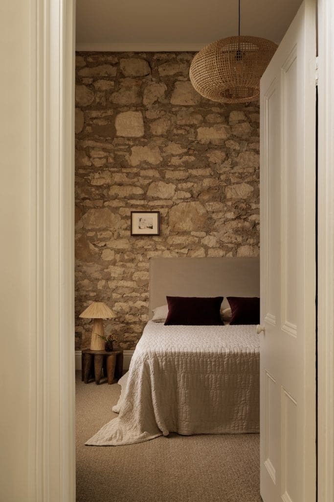 Bedroom with limestone wall at Coastal Alchemy by The Stylesmiths