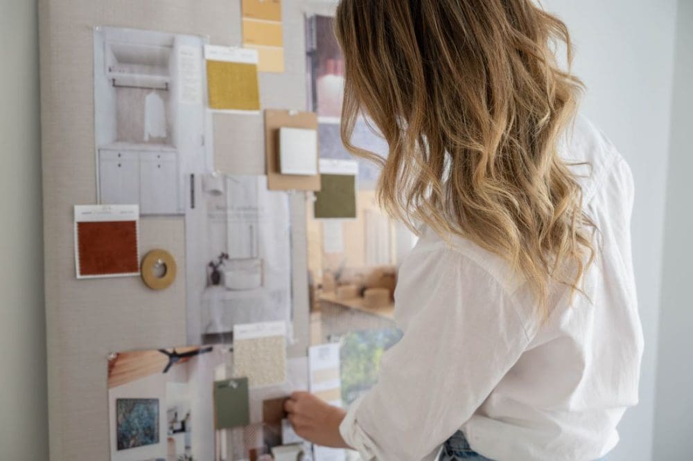 Gina Beschorner arranging fabric swatches, paint samples and interior images on a design mood board.