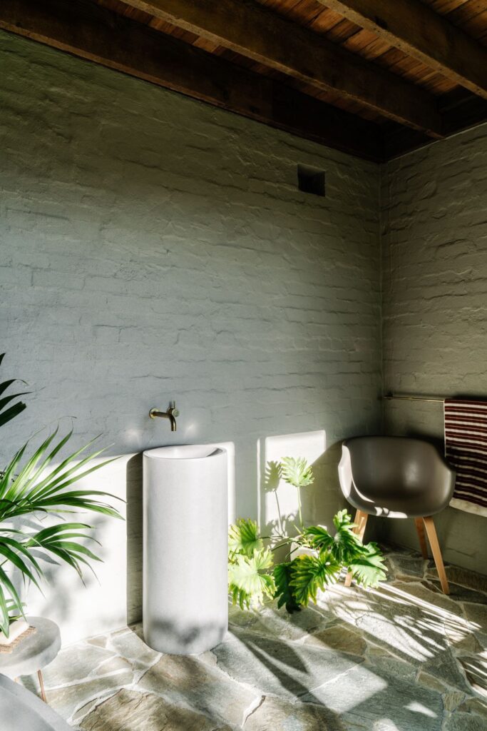Freestanding basin with brass tapware, white painted brick walls and natural stone flooring in Mountain House by Breathe, photographed by Marnie Hawson.