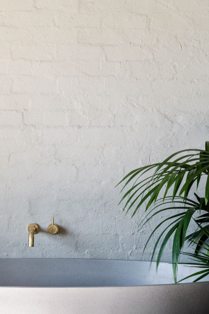 Freestanding bath with brass wall tapware against white painted brick wall in Mountain House by Breathe, photographed by Marnie Hawson.