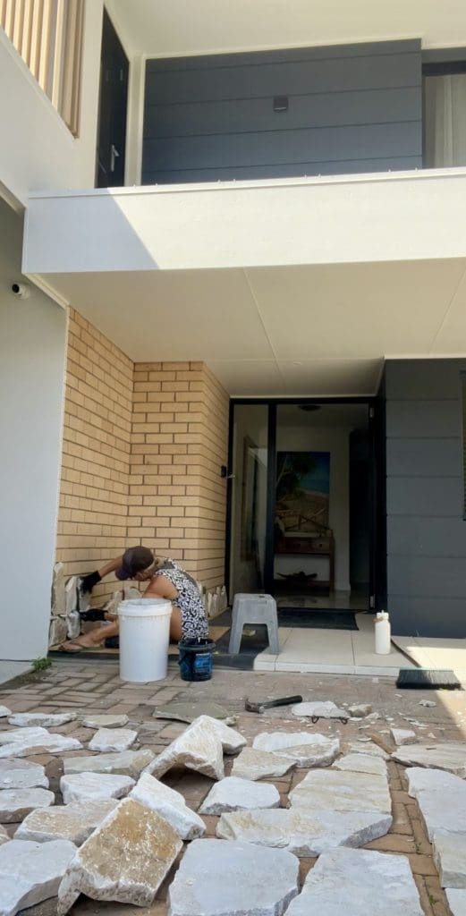 DIY stone wall makeover by Bec Riley from Rileygoodadventures - applying the first pieces of stone