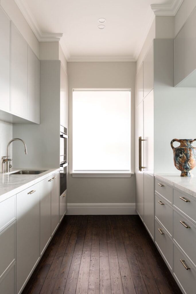 Bright galley kitchen with marble benches and brass handles