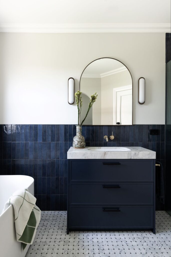Navy bathroom vanity with arched mirror and marble top