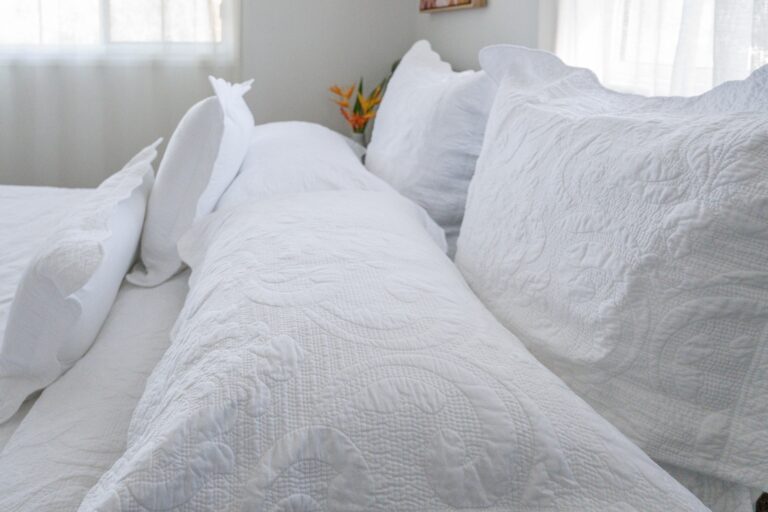 Close-up of white quilted bedding and pillows, with soft textures and natural light.