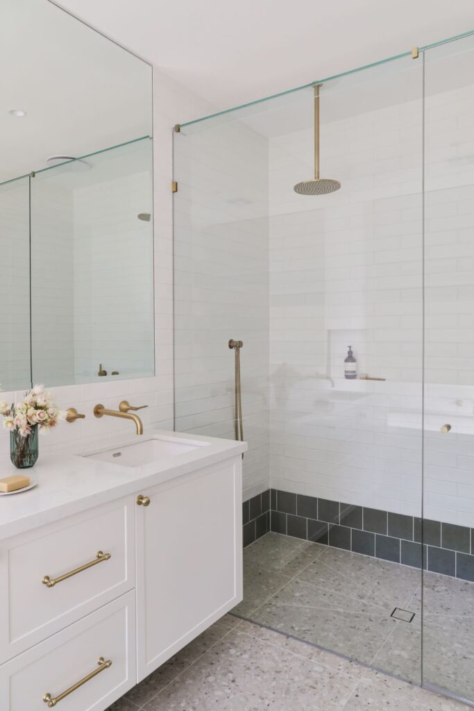 Bathroom detail with brass tapware glass shower and subway tiles