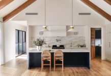 A modern farmhouse retreat designed for family living Modern farmhouse kitchen with timber beams and marble splashback