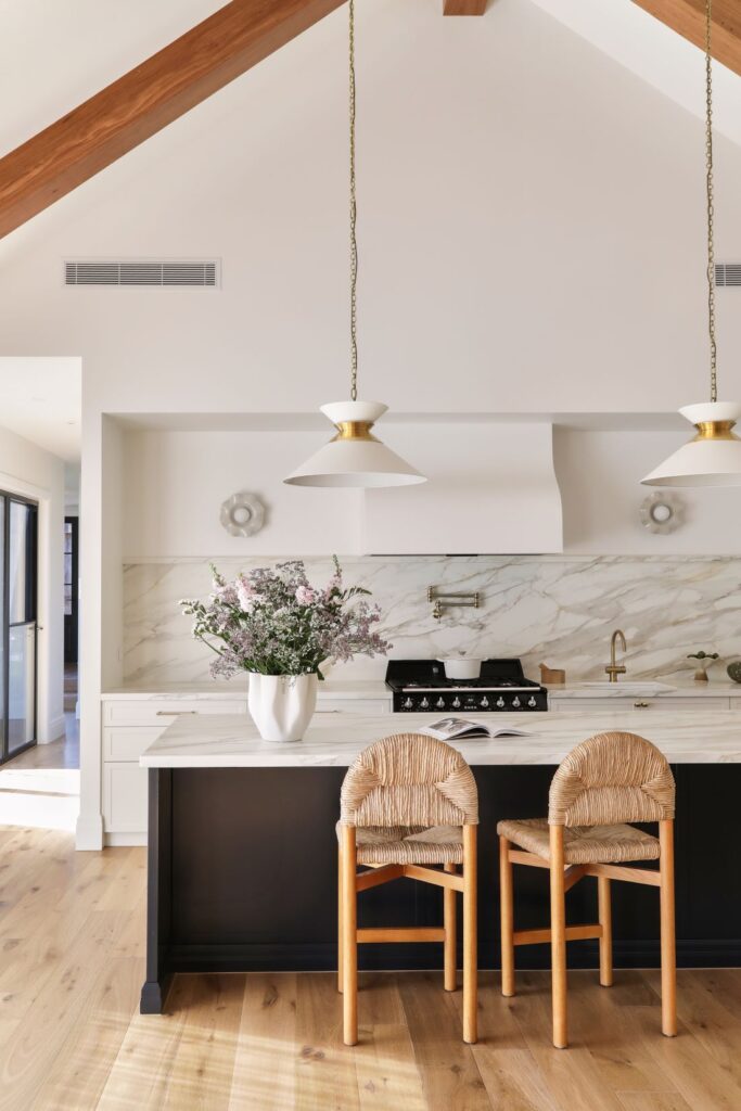 Kitchen island with woven bar stools and marble splashback