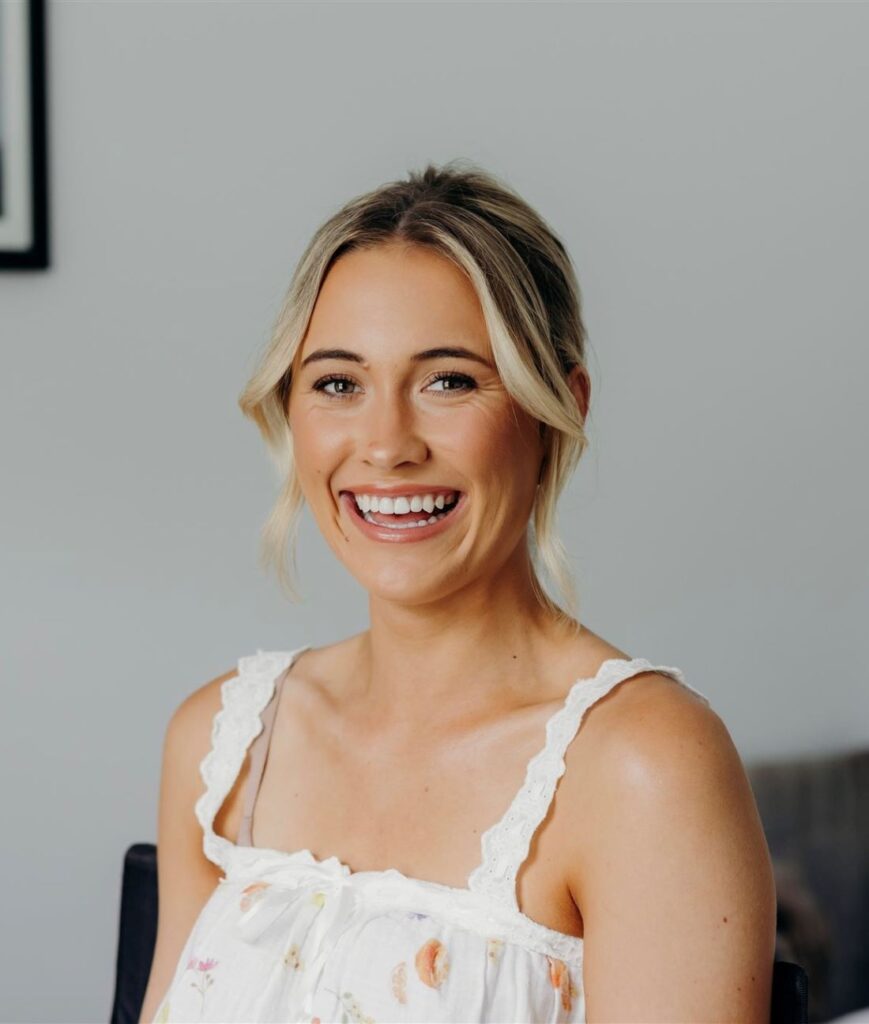 Portrait of Adele Auchterlonie, a Tasmanian abstract expressionist artist, smiling and wearing a floral top.