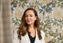 The hand drawn wallpaper and textile designs from Patricia Braune Patricia Braune, a skilled interior designer and surface artist, stands confidently in a white blazer against a botanical print wallpaper, showcasing her design expertise.