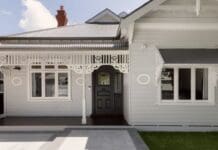 Rental property security: Practical ways landlords and tenants can improve home security A charming traditional home exterior featuring intricate woodwork, a dark front door, and large windows, with a beautifully paved entryway.