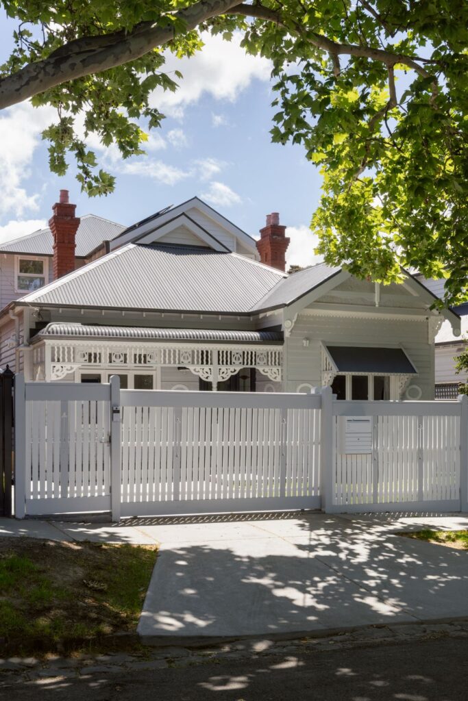 A traditional home with a beautifully detailed facade and a white picket fence surrounding the front yard