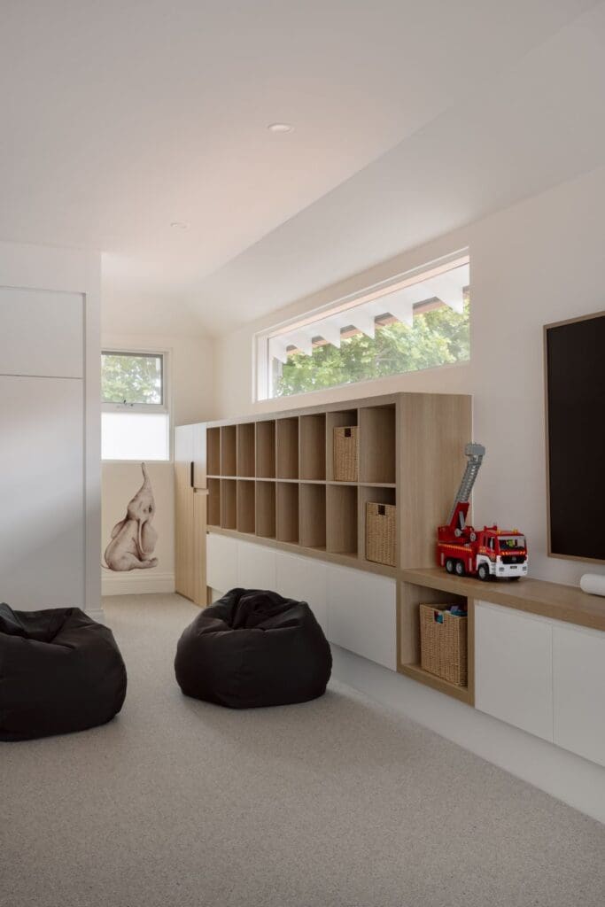 A spacious and well-organised kid's playroom featuring a large storage unit with cubby shelves