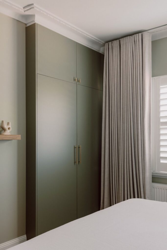 Muted green wardrobe joinery with knurled brass door pulls